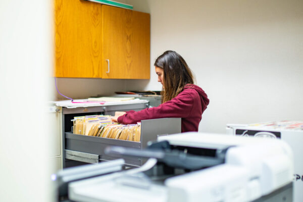 A student worker looks through a file cabinet in an office on WSU campus.