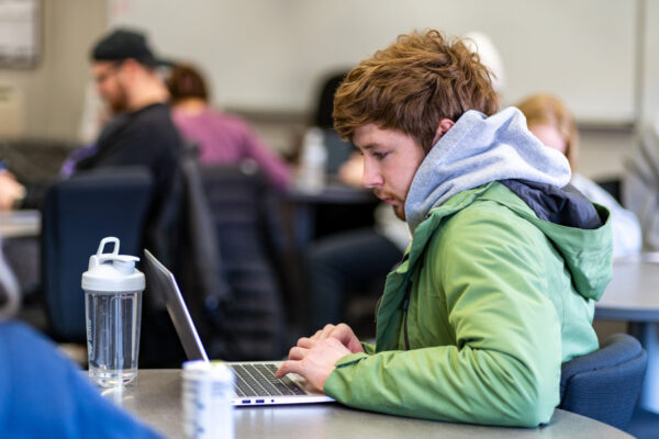 A male student uses a laptop in a classroom on WSU campus.