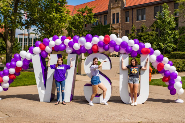Students pose by the WSU letters and a balloon arch on the WSU campus.