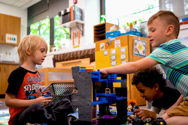 Three kids play with toys together in the WSU Children's Center.