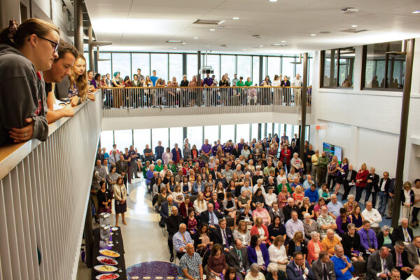 A large group of people gather for a presentation in the Helble Hall Atrium.