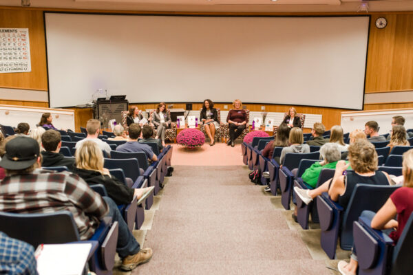 A group of people listen to a panel of speakers in an auditorium at WSU.