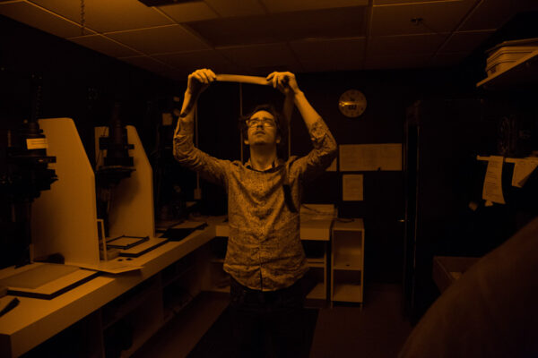 A student holds up a photo film strip in the campus dark room.