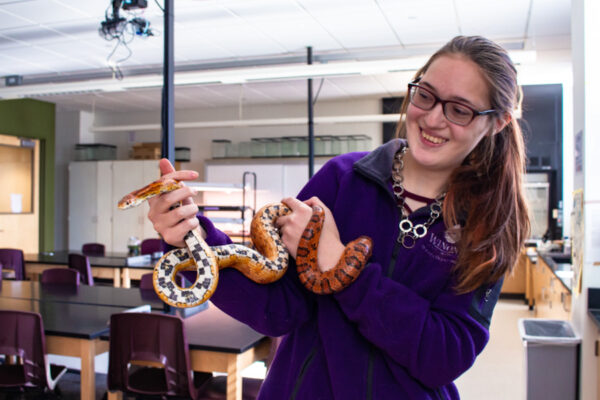 A student holds a snake in the animal care facility at WSU.