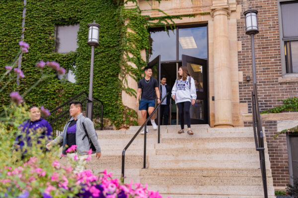 Students exit Phelps Hall after class on a sunny day.