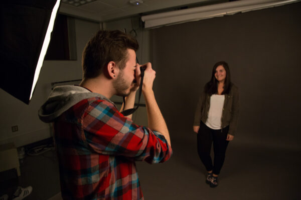 A student photographer takes a portrait in the campus photo studio.