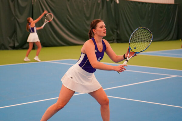 A WSU athlete prepares to hit a tennis ball at the tennis courts.