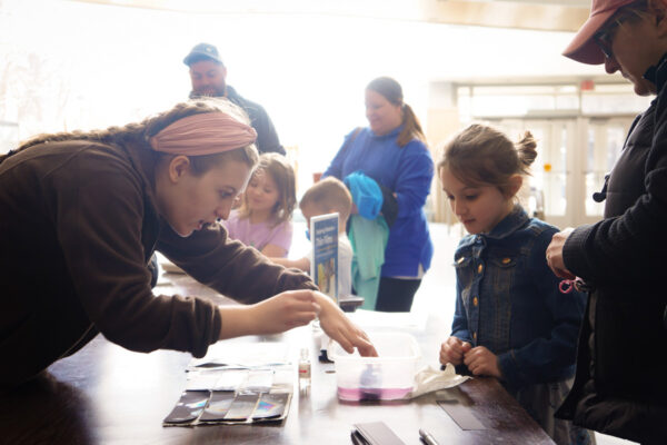 A student demonstrates a science experiment with a kid at an event on the WSU campus.