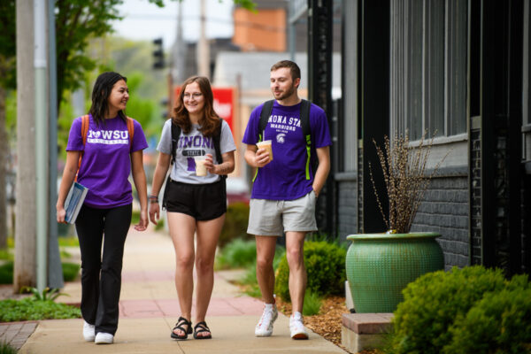 Student walk past shops while chatting.