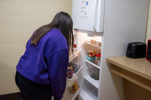 A student opens a fridge in a kitchen in Conway Hall.