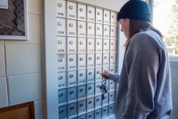 A student opens their private mailbox in the mail area of Conway Hall.