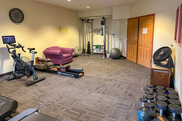 A workout room with weightlifting equipment and treadmills in East Lake Apartments.