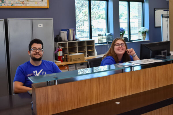 Two student workers sit at the front desk in Kirkland-Haake Hall.