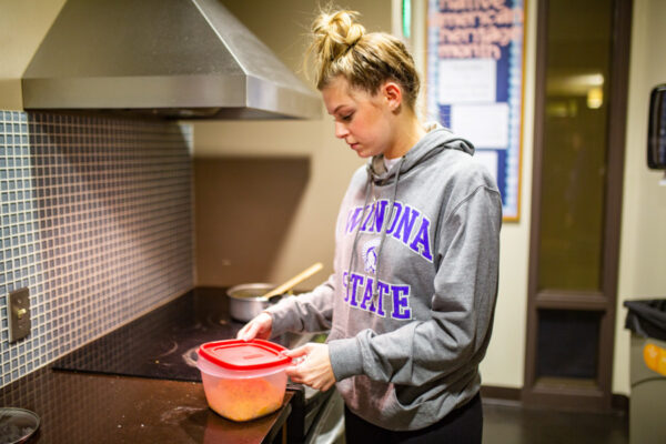 A student prepares a meal in a kitchen in Kirkland-Haake Hall.