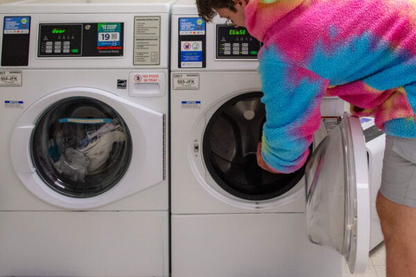A student opens a washing machine in the laundry room in Kirkland-Haake Hall.