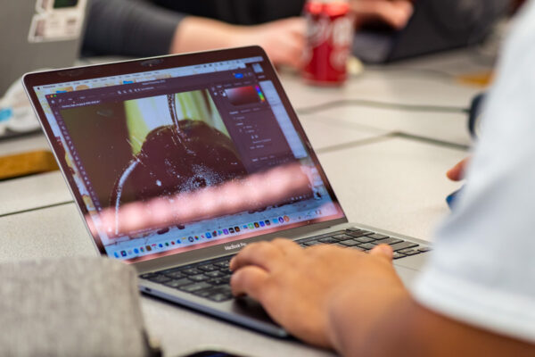 A person works in a graphic design program on a laptop.