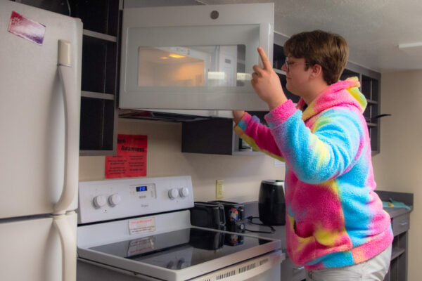 A student uses a microwave in a kitchen in Morey-Shepard Hall.