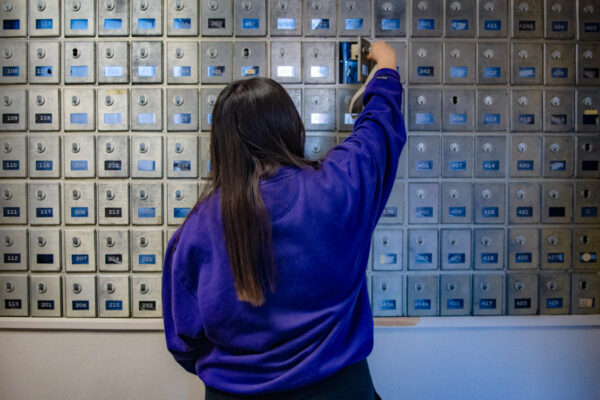 A student opens their private mailbox in the mail area of Morey-Shepard Hall.