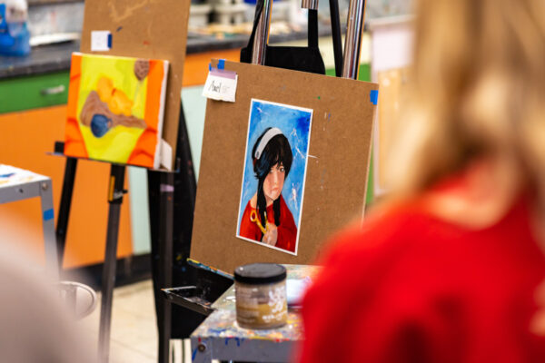 Students observe a painting hung on an easel in the Painting Studio.