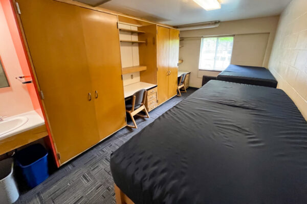 A move-in ready room with two lofted beds along the wall across from built-in closets and desks in Prentiss-Lucas Hall.