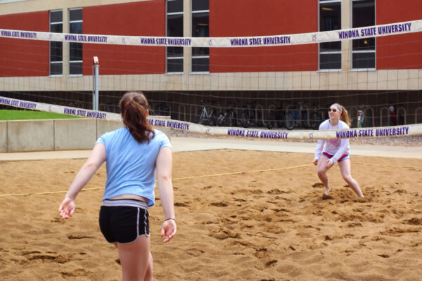 Two students play on the sand volleyball court outside Prentiss-Lucas Hall.
