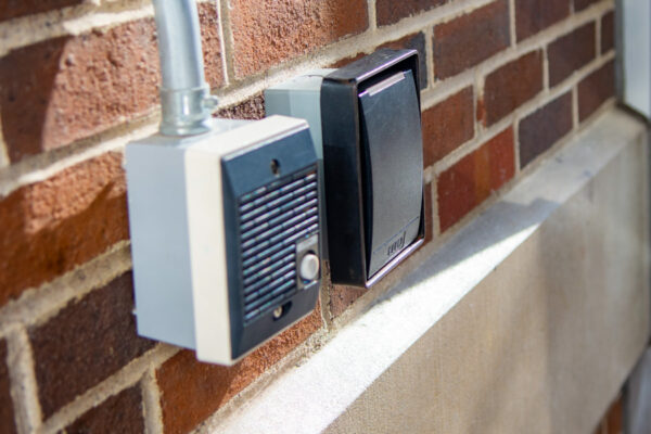An intercom and key card scanner are installed outside a door for a residence hall.