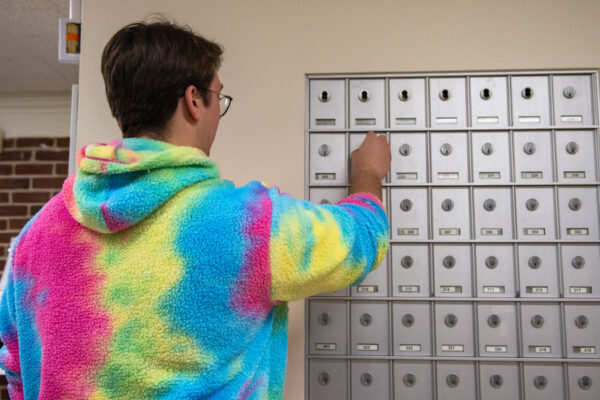 A student opens their private mailbox in the mail area of Richards Hall.