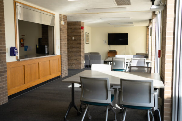 A lounge with tables, chairs, a couch, and a tv in Sheehan Hall.