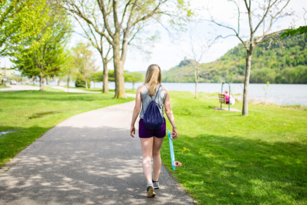 A student walks down a paved path alongside Lake Winona.