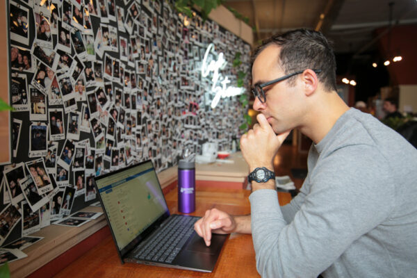 A student works on a laptop in a coffee shop.