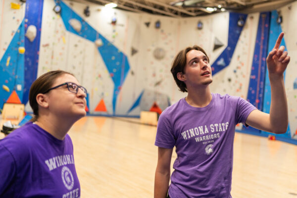 Two students look up at the climbing wall in the WSU Climbing Center.