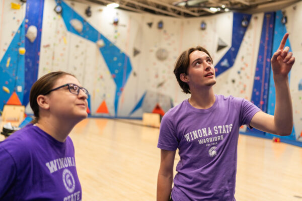 Two students look up at the climbing wall in the WSU Climbing Center.