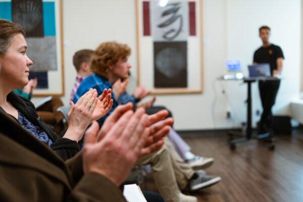 An audience claps after a student gives a presentation.