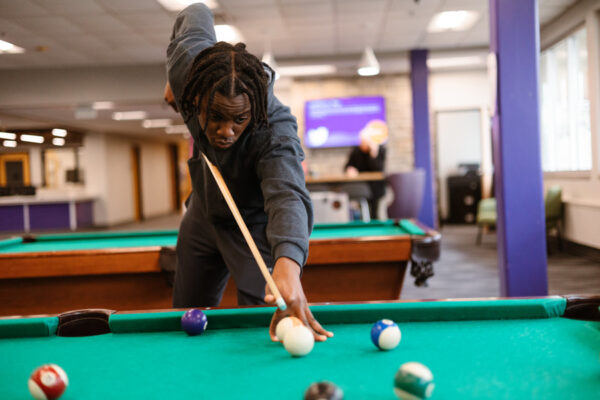 A male student plays pool in a lounge in Kryzsko Commons on the Winona campus.