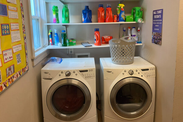 The laundry room in the WSU Sustainability House with a washer, dryer, and storage shelves.