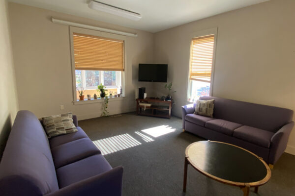 The living room in the WSU Sustainability House with couches, a wall-mounted tv, and coffee table.