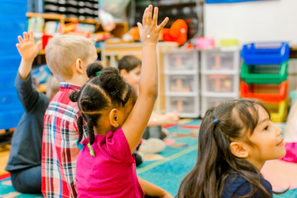 A child raises their hand in a classroom.