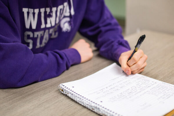 WSU student writing in a notebook.