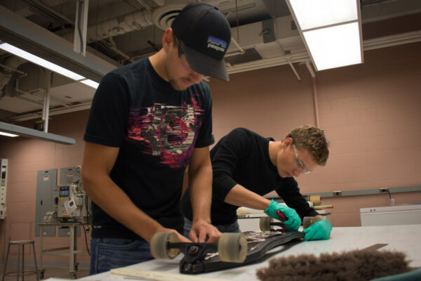 Two students work on a skateboard design in the composite materials lab.